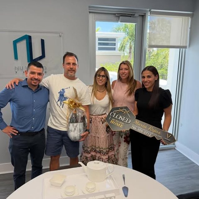 Maria with clients at a closing, holding an oversized key